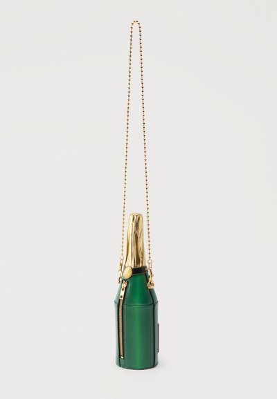 Πράσινη τσάντα χειρός σε σχήμα μπουκαλιού σαμπάνιας με χρυσή επένδυση στο πάνω μέρος, λεπτομέρεια φερμουάρ και λουράκι από χρυσή αλυσίδα.