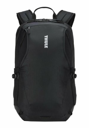 Sac à dos noir de la marque Thule avec bretelles rembourrées, poignée supérieure, compartiment avant zippé et sangles de réglage latérales.