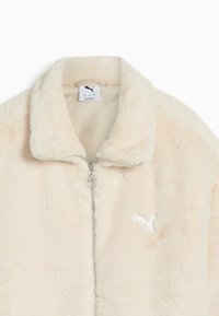 Beige fluffy zip-up jacket with stand collar and white Puma logo embroidered on the chest.