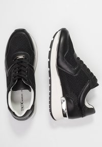 Czarne trampki z siateczkową cholewką, skórzanymi akcentami i teksturowaną gumową podeszwą. Posiadają srebrne dodatki i sportową sylwetkę.