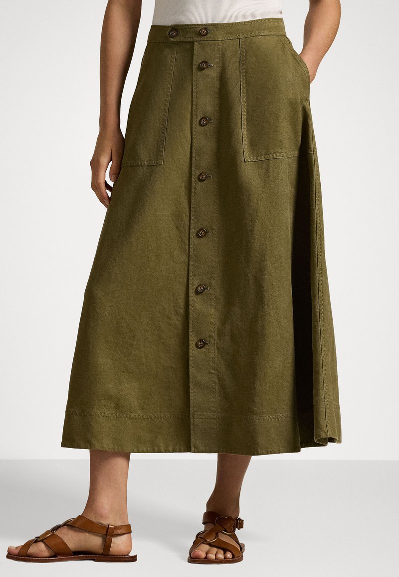 Falda verde oliva, de longitud hasta la rodilla, hecha de una tela suave, con frente de botones, dos bolsillos grandes y una abertura lateral para mayor libertad de movimiento.