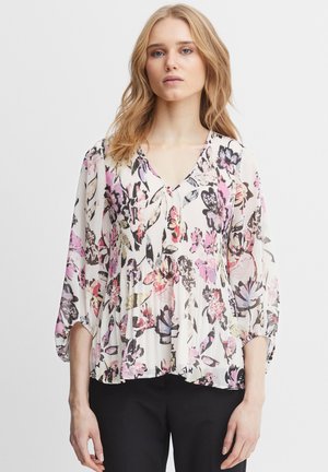 Blumenbluse mit V-Ausschnitt, aus leichtem Stoff gefertigt. Verfügt über gepuffte Ärmel und eine fließende Silhouette in den Farbtönen Rosa, Schwarz und Creme.