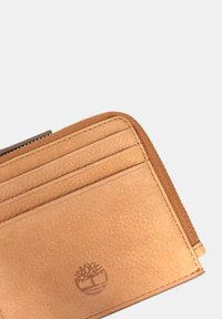 Portafoglio in pelle marrone chiaro con più slot per schede e un compartimento con zip. Include dettagli con logo impresso e superficie testurizzata.