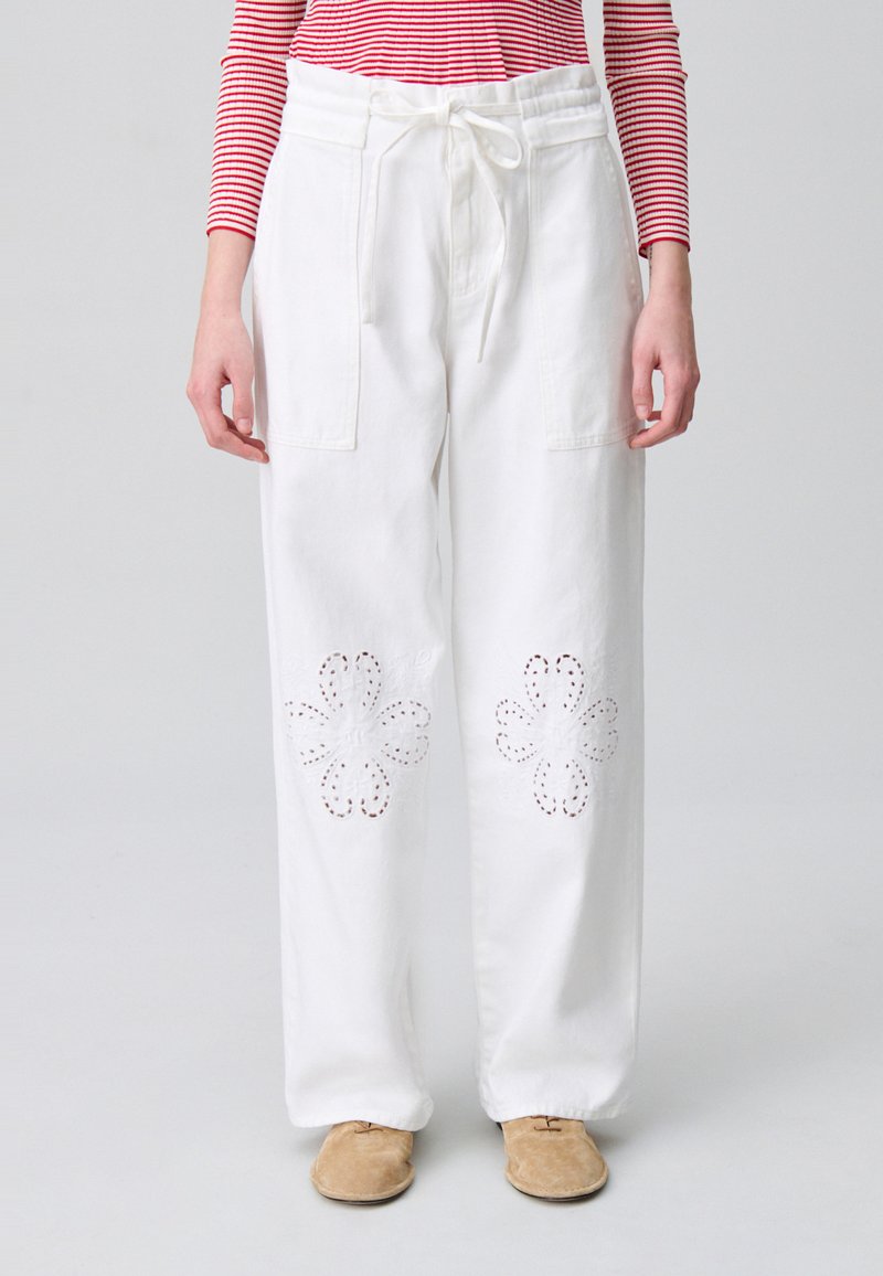 Pantalones de pierna ancha blancos con recortes en forma de flor en el dobladillo, que presentan una cintura con cordón y bolsillos laterales.