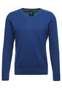 Blå stickad tröja med V-ringning, långa ärmar, ribbade ärmmuddar och nederkant, med en strukturerad yta och subtil logotypdetalj på bröstet.