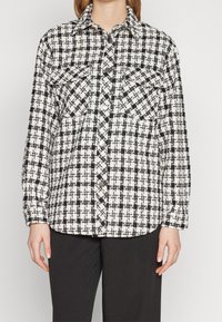 Sort-hvid ternet flannel skjorte med krave, to bryst lommer og trykknapper, med en afslappet pasform og lange ærmer.