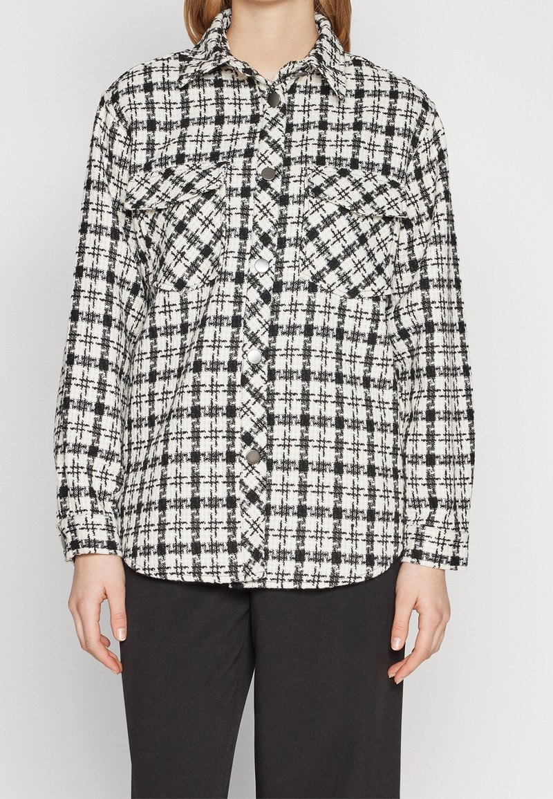 Sort-hvid ternet flannel skjorte med krave, to bryst lommer og trykknapper, med en afslappet pasform og lange ærmer.