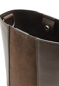 Brązowa torba typu tote z zamszu i skóry, z gładką powierzchnią zewnętrzną, widocznym przeszyciem i zatrzaskiem u góry.