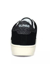 Sneaker in suede nera con un accento a tinta unita sul tallone glitterato, logo "SUN68" sul retro e suola in gomma bianca. Texture liscia, design a profilo basso.