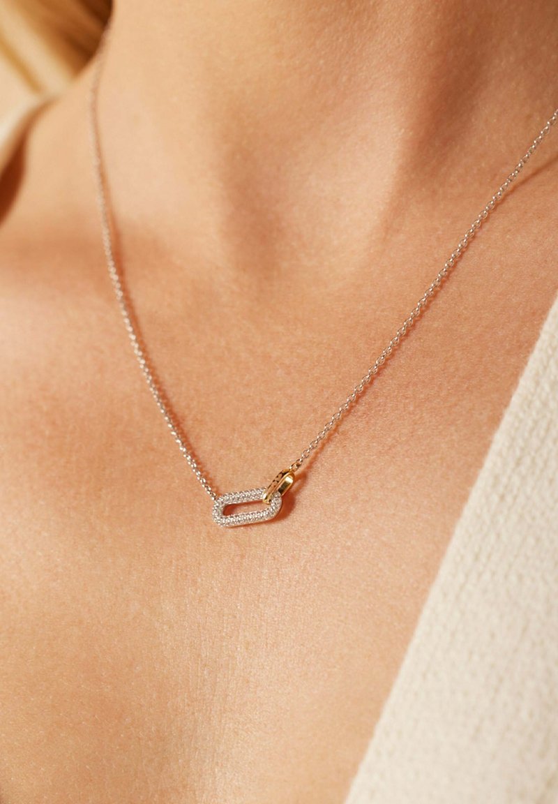 Zilveren ketting met een rechthoekige hanger met een gouden accent, versierd met kleine sprankelende stenen.