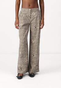 Leopardenmusterweite Hosen in einem hellbraunen und schwarzen Farbschema mit einer glatten Textur, ausgestattet mit seitlichen Taschen und einer entspannten Passform.