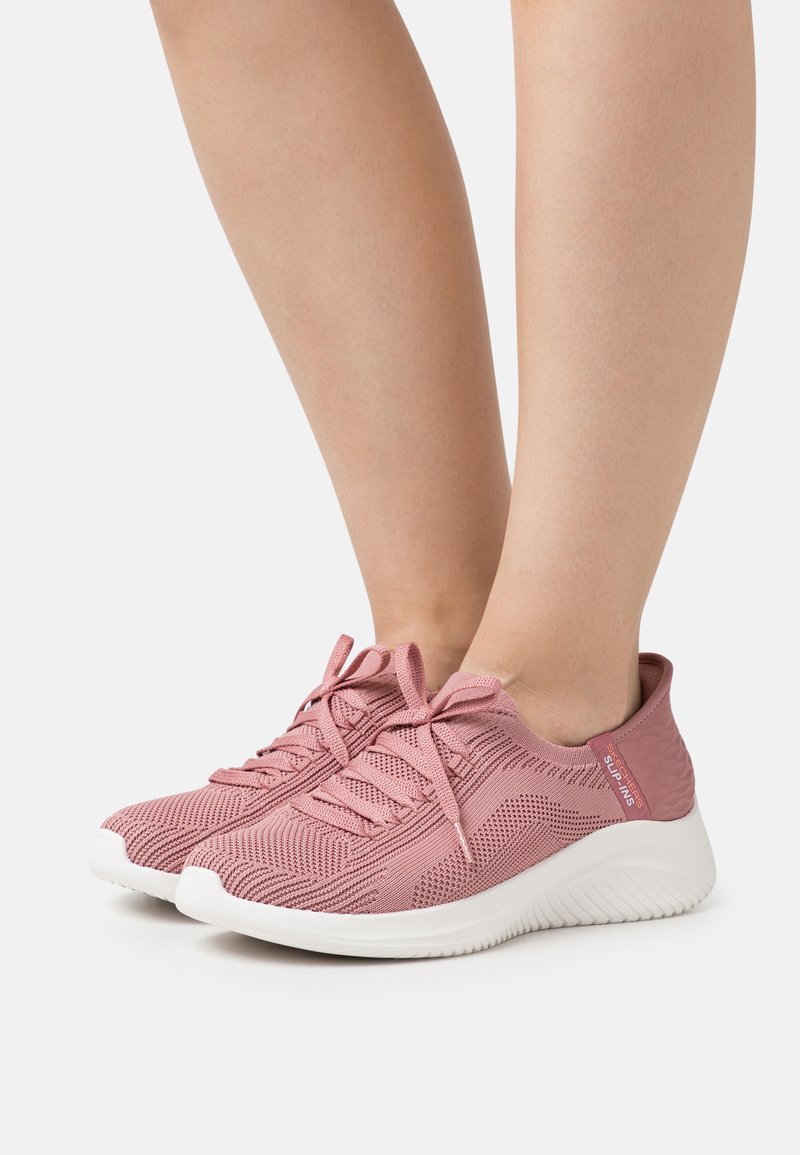Light pink athletic shoes with a breathable mesh upper, lace-up design, white sole, and textured accents near the heel.