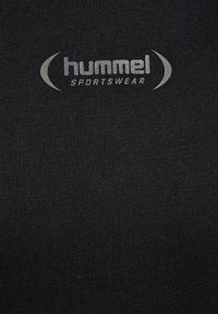 Svart sporttyg med ribbad textur, med en ljusgrå "hummel"-logotyp och böjda accenter ovanför texten.