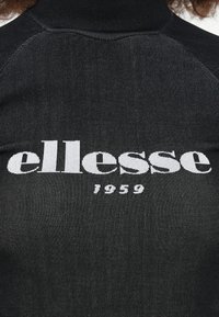 Fekete bordás garbó, kiemelkedő fehér "ellesse" logóval és "1959" felirattal, kontrasztos varrással a vállakon.