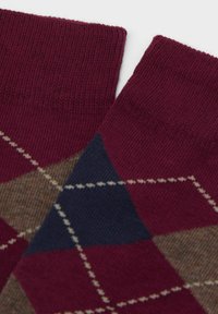 Bordeaux og marineblå argyle-mønstrede sokker med ribbede manchetter, fremstillet af et blødt, tekstureret stof og diagonale linjer i lyst brunt og creme.