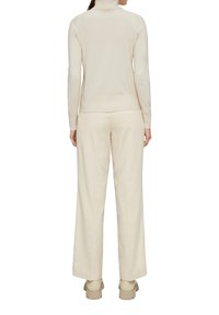 Lichtbeige turtleneck trui en bijpassende wijde broek. Zachte textuur, minimalistisch ontwerp en subtiele ribbeling bij de kraag en zoom.