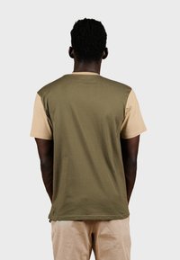 Camiseta de manga corta con cuerpo en verde oliva y mangas beiges, hecha de una tela suave. Presenta un escote redondo y un ajuste relajado.