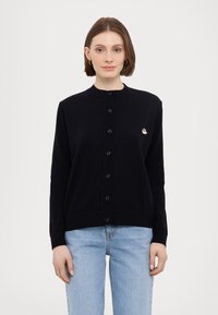 Črn kardigan s okroglim izrezom in zapiranjem na gumb, ki vsebuje majhen vezen design na prsih ter rebraste manšete in spodnji rob.