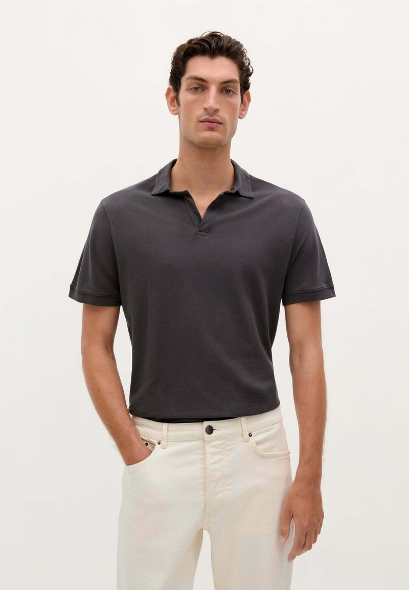 Mørkegrå polo med krave og korte ærmer, lavet af blødt stof, parret med lyse jeans.