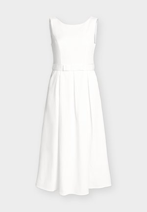 Biała sukienka midi bez rękawów z teksturowanej tkaniny, dopasowany gorset, pasek z małą kokardką i plisowana spódnica w kształcie litery A na neutralnym tle.
