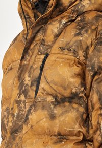 Braune, gemusterte Daunenjacke mit einem Reißverschluss-Brusttasche. Sie weist eine Mischung aus strukturiertem Stoff und glatten Oberflächen auf und ist mit "O'Neill" gebrandet.