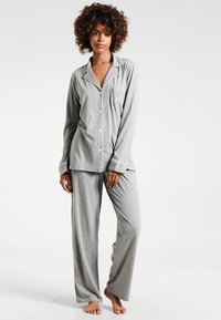 Conjunto de pijama cinza composto por uma camisa de botão de manga longa com um bolso e calças largas combinando, feito de um tecido leve e suave.