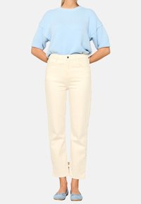 Ljusblå stickad tröja med korta ärmar, tillsammans med krämfärgade raka jeans. Aqua balettskor fulländar outfiten.