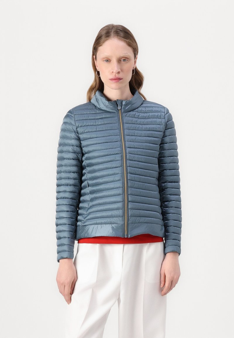 Lys blå pufferjakke med horisontal quiltet design, stående krave og frontlynlås. Slim fit med en glat, blank overflade.
