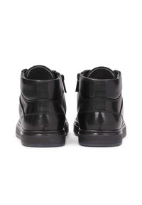 Črne usnjene gležnjarje z gladko površino, ki imajo zadnji zadrgo, oblazinjeno ovratnik in teksturirane bočne panele za podporo.