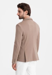 Beige maßgeschneiderter Blazer aus glattem Stoff, einreihiges Design, mit Reverskragen und Knopfverzierungen an den Ärmeln, Sicht auf die Rückansicht.