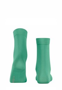 Grüne knöchellange Socken aus glattem Stoff, ausgestattet mit einem gerippten Bund und nahtlosem Design, verziert mit einem kleinen Logo an der Sohle.