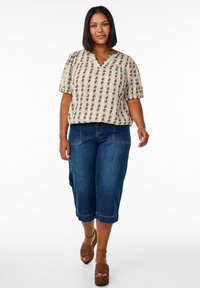 Flowy beige blouse with vertical stripes and floral patterns, paired with knee-length blue denim culottes and brown woven platform sandals.