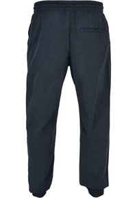 Pantalon bleu marine à taille élastique avec poche arrière, poches latérales et poignets élastiques aux chevilles.
