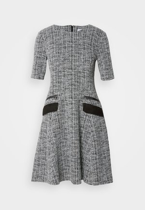 Grijs en wit gestreepte jurk met korte mouwen, aansluitend lijfje, uitlopende rok en zwarte suède zakaccenten. Achterste ritsclosure.