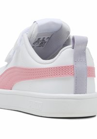 Zapatilla blanca con franjas de acento en rosa y tacón trasero gris. Presenta un material sintético suave y un forro texturizado en el interior. Suela plana blanca.