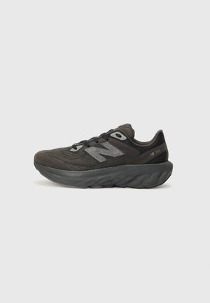 Baskets de sport gris foncé avec une semelle épaisse rembourrée, dessus en mesh, lacets à l'avant et logo New Balance sur le côté.