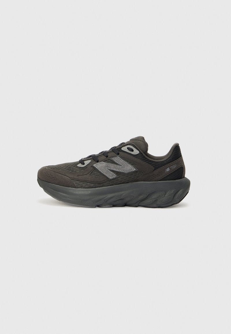 Baskets de sport gris foncé avec une semelle épaisse rembourrée, dessus en mesh, lacets à l'avant et logo New Balance sur le côté.