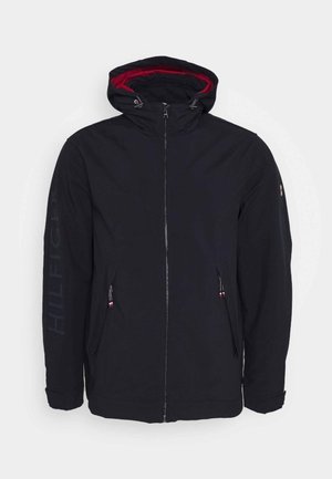 Czarna kurtka z kapturem podszytym czerwonym materiałem, z dwoma bocznymi kieszeniami na zamek oraz nadrukiem „HILFIGER” w ciemnoniebieskim kolorze na lewym rękawie. Posiada standardowy krój.