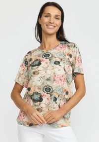 Kortermet T-skjorte med blomstermønster og rund hals, laget av myk stoff. Har livlige rosa, blå og sorte blomster mot en beige bakgrunn.