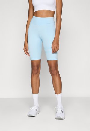 Pantaloni scurți de ciclism azul deschis, cu o talie înaltă și o textură netedă. Prezintă dungi orizontale subtile și sunt asortați cu pantofi sport albi și șosete.