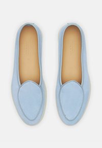 Lichtblauwe suède instappers met een ronde neus, minimale stiksels en een zachte beige binnenkant, voorzien van een flexibele witte zool.