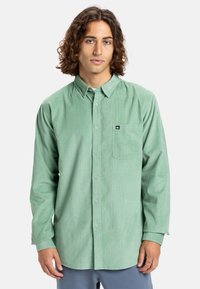Lichtgroene ribfluwelen overhemd met een button-down kraag, lange mouwen, een enkele borstzak en een klein merklabel op de zak.