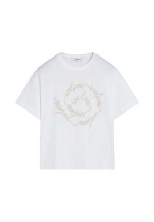 T-shirt blanc à manches courtes avec une coupe ample et un texte cursif beige formant une spirale à l'avant.
