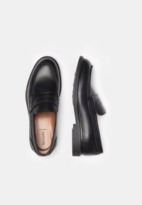 Mocassini in pelle nera con punta arrotondata, caratterizzati da un design cucito e una fascia accentata testurizzata. Parte superiore liscia e suola in gomma resistente.