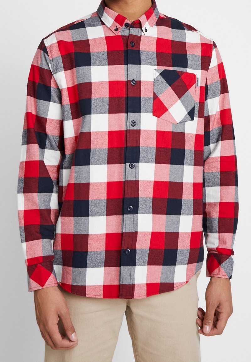 Rood, marineblauw, grijs en wit geruit flanellen overhemd met knoopkraag, borstzak, en lange mouwen, voorzien van een afgeronde zoom en knopen.