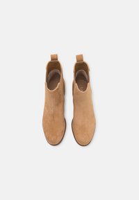 Suedefärgade ankelstövlar i en slät textur, med elastiska sidopaneler och dragflikar för enkel påtagning. Har en enkel, strömlinjeformad design.