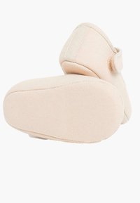 Miękkie beżowe buty z tkaniny o zaokrąglonym kształcie. Posiadają rzep oraz teksturowaną gumową podeszwę dla lepszej przyczepności. Minimalistyczny design, bez wzorów.