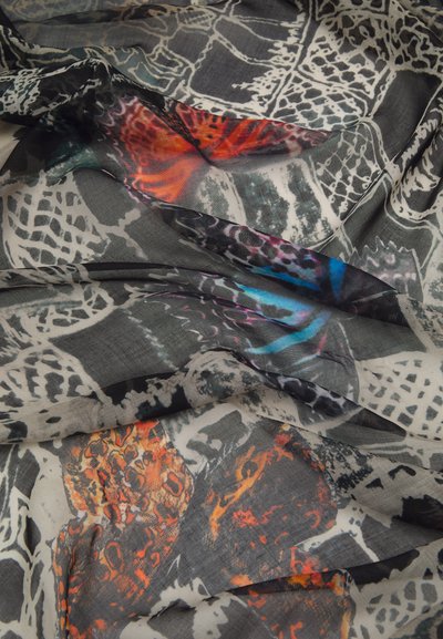 Foulard léger présentant un mélange de motifs noirs, blancs et d'orange et bleu vibrants, avec une texture lisse et fluide.