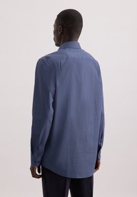Donkerblauwe longsleeve shirt met een witte stippenpatroon, op maat gesneden fit, ronde zoom en met knopen aan de manchetten, gezien van de achterkant.