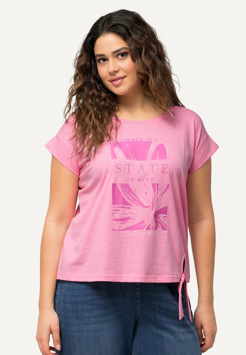 Růžové tričko s krátkým rukávem, které má květinovou grafiku a text "LETO JE STAV MYSLI." Doplňují ho boční šňůrky na lemu pro přidaný detail.